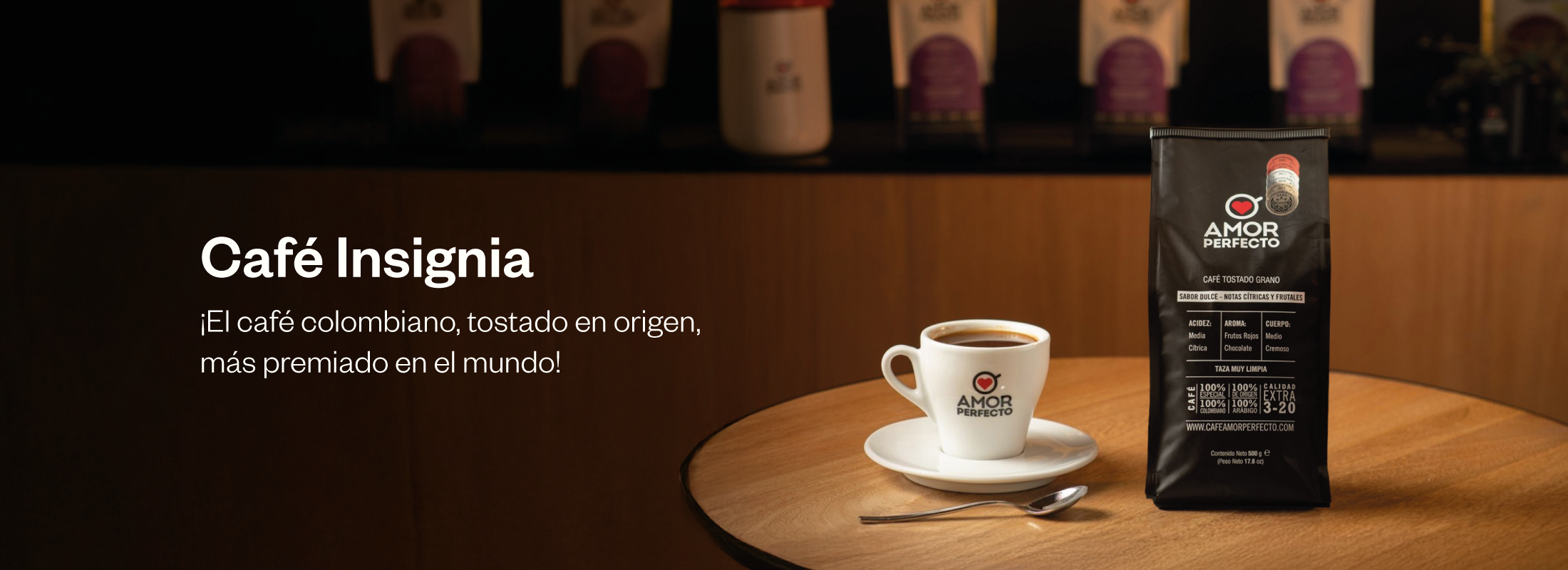 Café Insignia Amor Perfecto, el café colombiano tostado en origen más premiado del mundo, junto a una taza de café en mesa de madera.